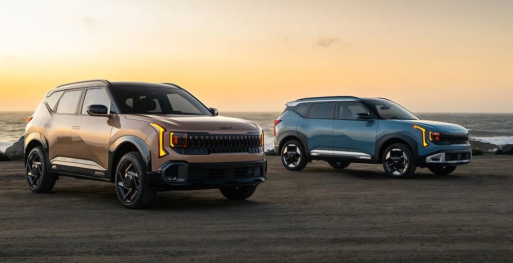 Two Kia Seltos SUVs parked on a beach at sunset